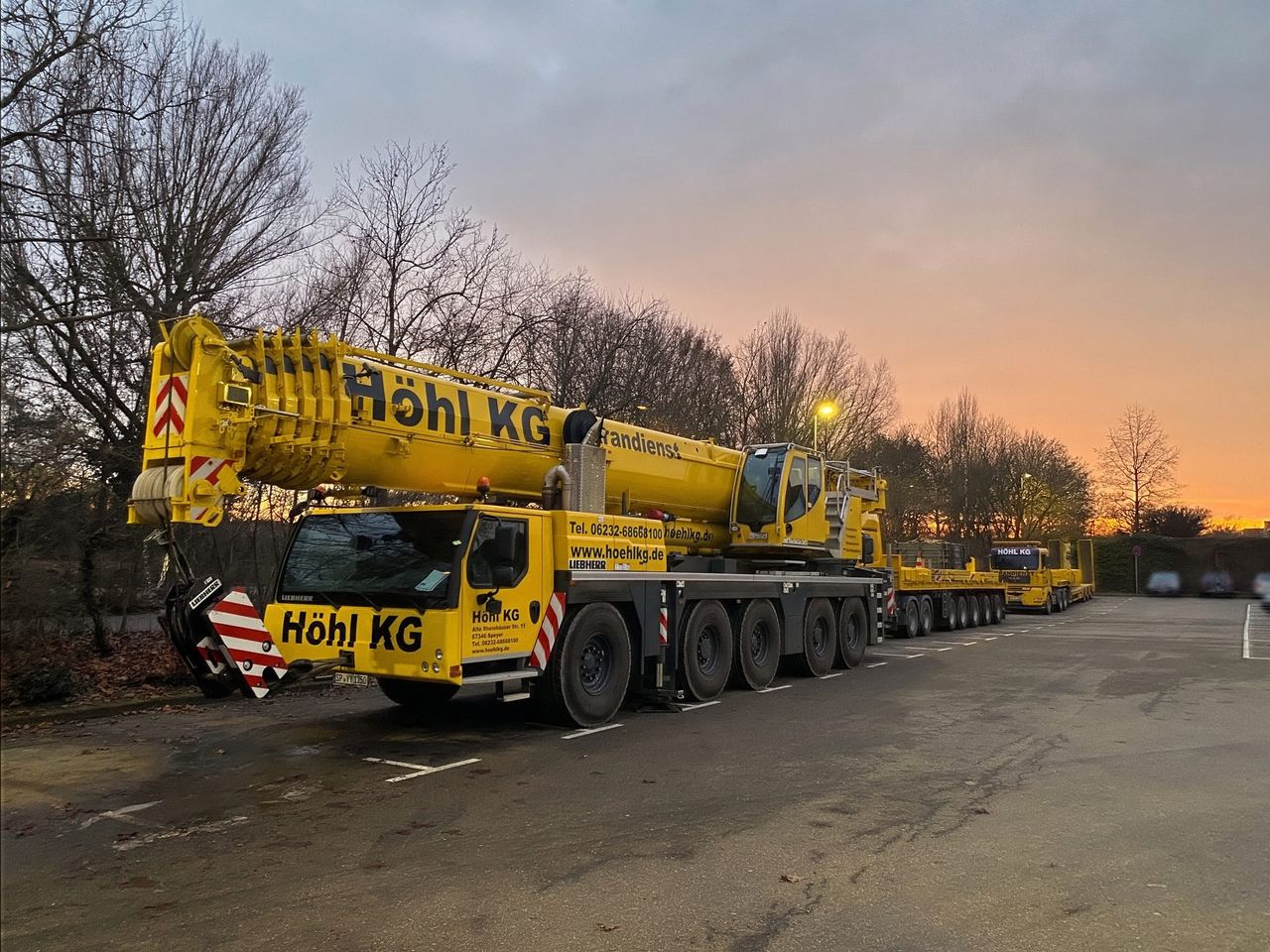 Liebherr-Mobilkran der Höhl Gruppe mit Tiefladern im Abendlicht